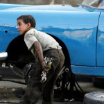 Egyptian boy helps fix an old car in front of a workshop in old Cairo